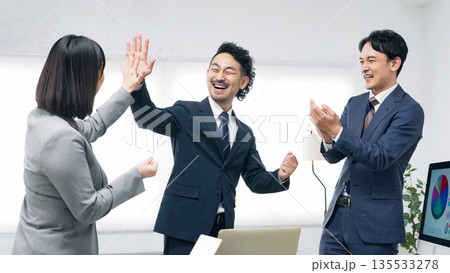 オフィスでハイタッチするビジネスパーソンのグループ 135533278
