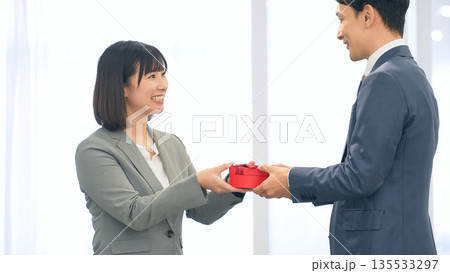 オフィスでプレゼントを渡すビジネスパーソン オフィスでプレゼントを渡すビジネスパーソン 135533297