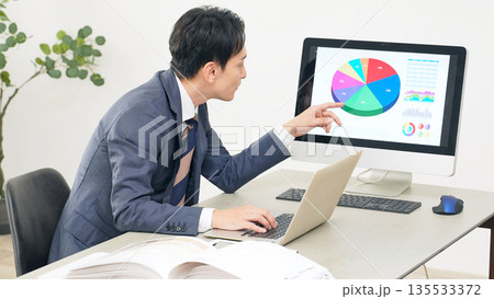 オフィスでPCを見ながら仕事する男性ビジネスパーソン オフィスでPCを見ながら仕事する男性ビジネスパーソン 135533372