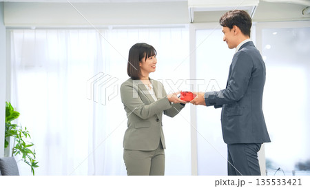 オフィスでプレゼントを渡すビジネスパーソン 135533421