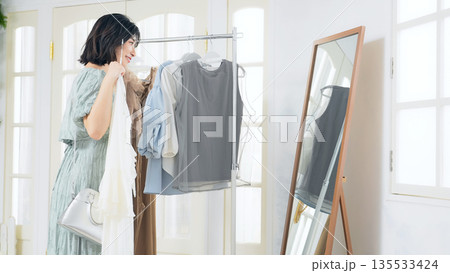 アパレルショップで鏡を見ながら洋服を選ぶ女性 135533424