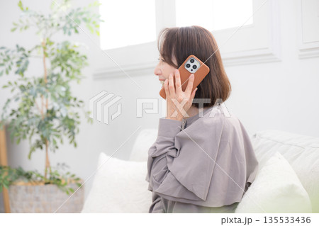 部屋でスマホで通話するシニア女性の横顔 部屋でスマホで通話するシニア女性の横顔 135533436