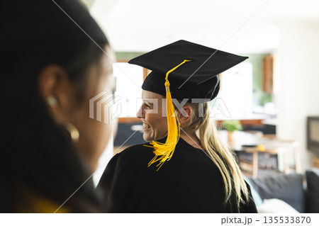 Graduating students wearing caps and gowns celebrating achievement at home 135533870