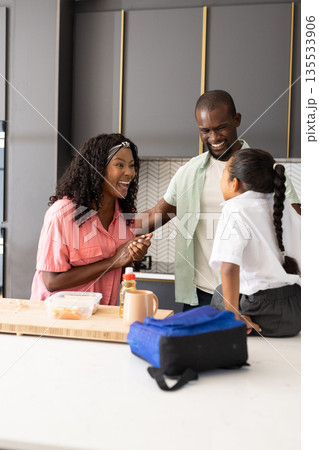 African American family in kitchen, smiling and preparing lunch together at home African American family in kitchen, smiling and preparing lunch together at home 135533906