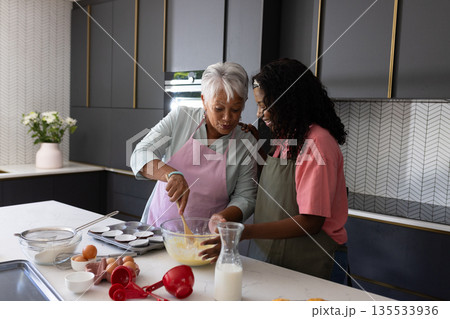 Baking together in kitchen, grandmother and granddaughter sharing joyful moment Baking together in kitchen, grandmother and granddaughter sharing joyful moment 135533936