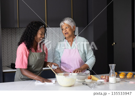Baking together in kitchen, African American women sharing joyful moments and laughter Baking together in kitchen, African American women sharing joyful moments and laughter 135533947