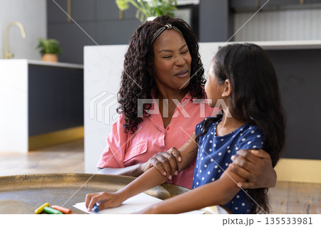 African American mother and daughter smiling while drawing together at home African American mother and daughter smiling while drawing together at home 135533981