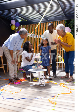 Celebrating birthday outdoors, family with cake and decorations, sharing joyful moments Celebrating birthday outdoors, family with cake and decorations, sharing joyful moments 135534019
