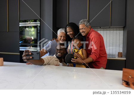 Family taking selfie together in modern kitchen, smiling and enjoying quality time 135534059