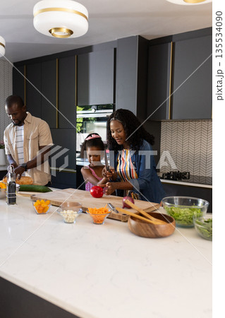 African American family preparing meal in modern kitchen, smiling and engaged African American family preparing meal in modern kitchen, smiling and engaged 135534090