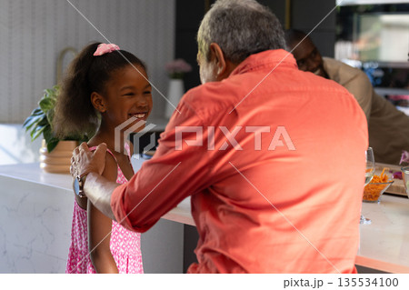 Grandfather and granddaughter sharing joyful moment together in modern kitchen 135534100