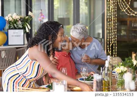 Celebrating retirement, African American family sharing festive meal and affection Celebrating retirement, African American family sharing festive meal and affection 135534153