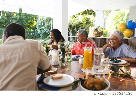 Family enjoying outdoor meal together, smiling and sharing stories at festive table 135534156