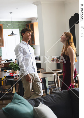 Teenagers laughing and enjoying drinks at home during lively celebration 135534818