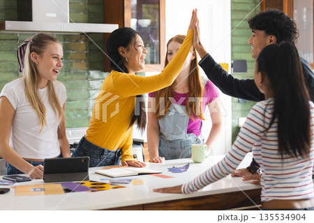 Teen friends high-fiving in kitchen, celebrating success with joyful expressions Teen friends high-fiving in kitchen, celebrating success with joyful expressions 135534904