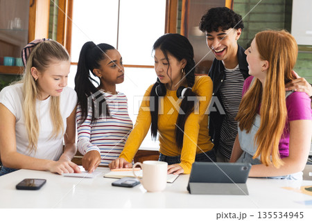 Teen friends collaborating on school project at home, using tablet and notes 135534945