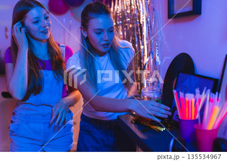Teen girls enjoying party snacks and drinks in vibrant celebration setting 135534967