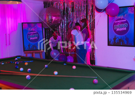 Decorating party room with balloons, teenagers creating disco theme for birthday event Decorating party room with balloons, teenagers creating disco theme for birthday event 135534969