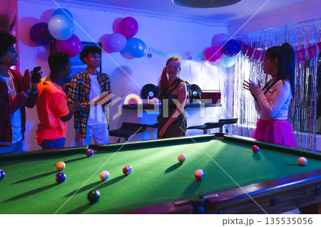 Teen friends celebrating birthday with pool table and colorful decorations at home Teen friends celebrating birthday with pool table and colorful decorations at home 135535056