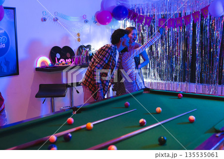 Teens taking selfie at birthday party near pool table with festive decorations 135535061