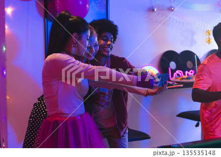 Teen friends taking selfies at vibrant party, enjoying fun and laughter together 135535148