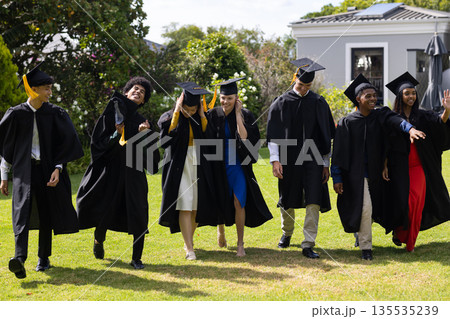 Graduating students in caps and gowns celebrating joyfully outdoors together Graduating students in caps and gowns celebrating joyfully outdoors together 135535239