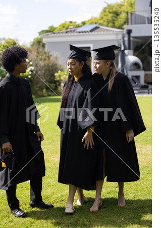 Graduating students in caps and gowns celebrating together outdoors, feeling joyful Graduating students in caps and gowns celebrating together outdoors, feeling joyful 135535240