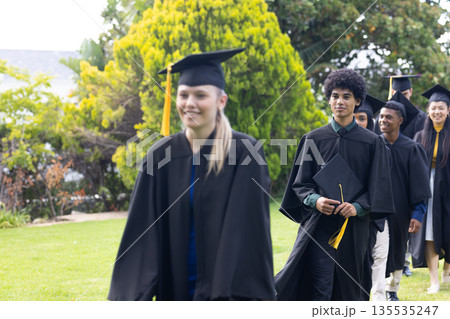 Graduating students in caps and gowns celebrating achievement together outdoors 135535247