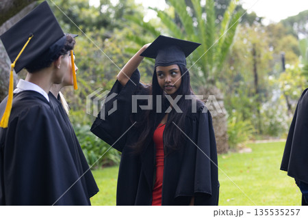 Teen graduates in cap and gown celebrating outdoors, enjoying their achievement Teen graduates in cap and gown celebrating outdoors, enjoying their achievement 135535257