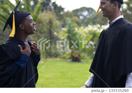 Graduates in caps and gowns celebrating success with joyful conversation outdoors Graduates in caps and gowns celebrating success with joyful conversation outdoors 135535260