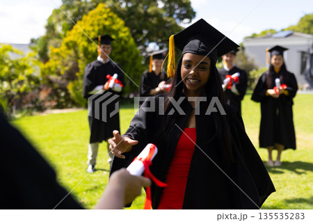 Graduating students in caps and gowns celebrating with diplomas outdoors Graduating students in caps and gowns celebrating with diplomas outdoors 135535283