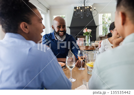 Laughing and conversing, friends at dining table during wedding celebration Laughing and conversing, friends at dining table during wedding celebration 135535442