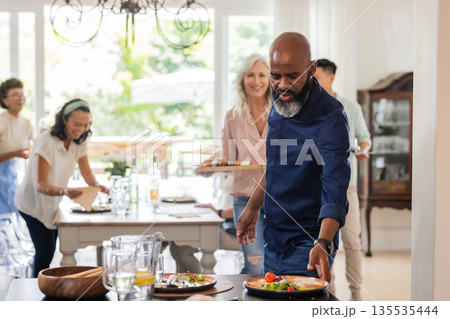 Guests enjoying delicious meal together at home, celebrating with joyful smiles Guests enjoying delicious meal together at home, celebrating with joyful smiles 135535444