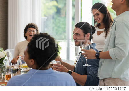 Friends laughing and enjoying drinks together at wedding reception indoors 135535447