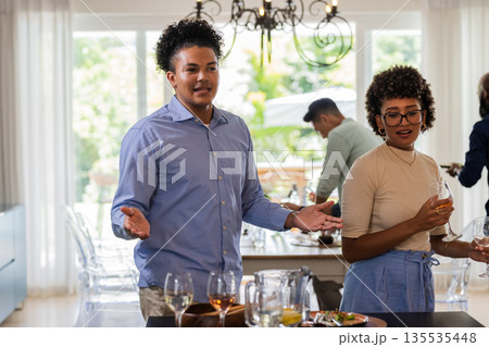 African American couple enjoying drinks and conversation at elegant indoor gathering African American couple enjoying drinks and conversation at elegant indoor gathering 135535448