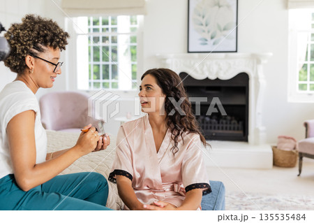 Bride in silk robe talking with makeup artist in elegant living room 135535484