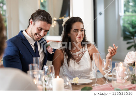 Bride and groom laughing together at wedding reception, enjoying joyful celebration Bride and groom laughing together at wedding reception, enjoying joyful celebration 135535516