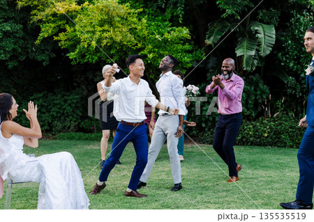 Guests joyfully dancing and celebrating together at outdoor wedding reception Guests joyfully dancing and celebrating together at outdoor wedding reception 135535519