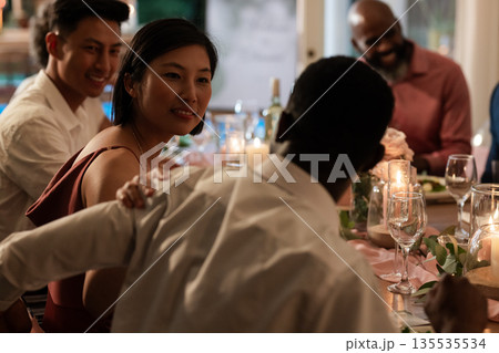 Guests enjoying lively conversation at elegant wedding dinner table with candles 135535534