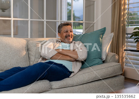 Relaxing on sofa, senior man smiling and enjoying peaceful afternoon at home 135535662