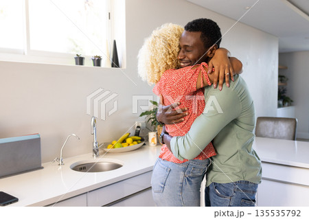 African American man and woman hugging in modern kitchen, expressing happiness African American man and woman hugging in modern kitchen, expressing happiness 135535792