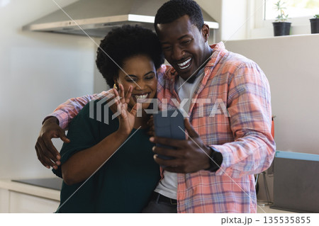 African American couple smiling and video chatting on smartphone in kitchen African American couple smiling and video chatting on smartphone in kitchen 135535855