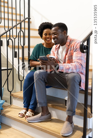 Smiling friends sitting on stairs, sharing smartphone and enjoying coffee together Smiling friends sitting on stairs, sharing smartphone and enjoying coffee together 135535905