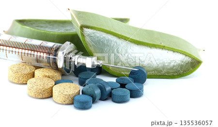 Syringe and pills next to aloe vera slices, representing natural medicine and healing 135536057