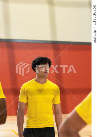 Male teammates practicing in gymnasium in yellow shirts and black shorts with red wall padding Male teammates practicing in gymnasium in yellow shirts and black shorts with red wall padding 135536250
