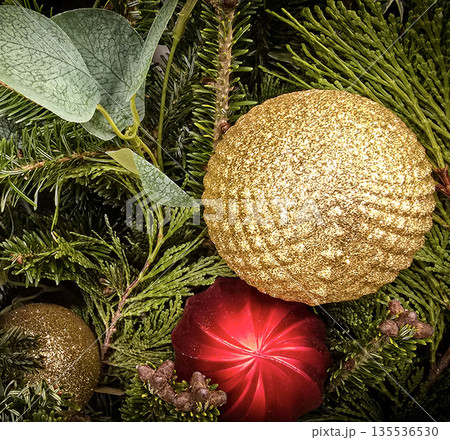 festive arrangement of glittering colorful Christmas ornament balls nestled in lush evergreen branches, creating a warm, celebratory mood perfect for holiday decor and seasonal stock photography 135536530