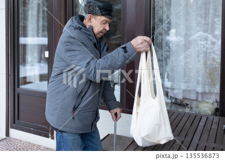 Elderly Man Walking With Cane In Snowy Courtyard 135536873