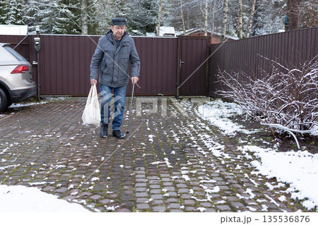 Elderly Man Walking With Cane In Snowy Courtyard 135536876