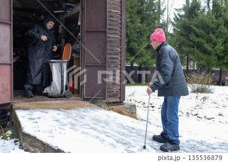 Two men disposing waste inside garage during winter Two men disposing waste inside garage during winter 135536879