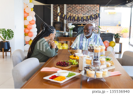 At home, African American couple celebrating retirement with conversation and snacks 135536940